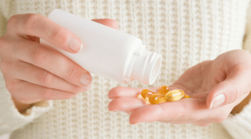 woman with bottle of vitamins or supplements featured