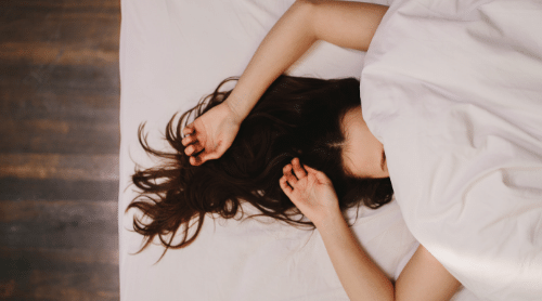 woman sleeping with covers over face featured