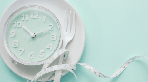 mint colored clock on white plate with fork and measuring tape featured