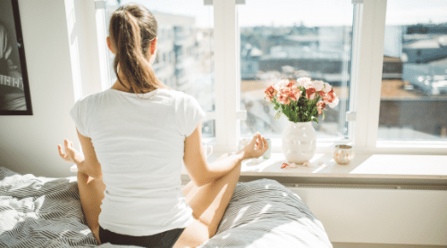 woman meditating on bed in morning featured